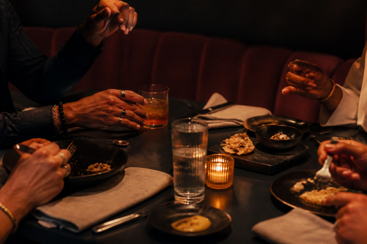 A relaxed late-night table gathering with drinks and small plates